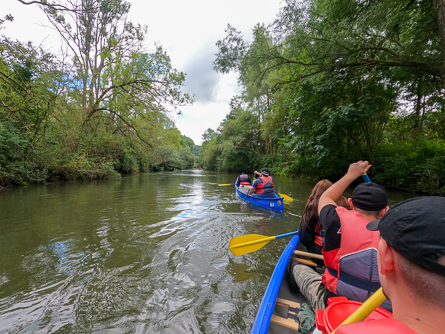 Gemeinsame Kanufahrt auf einem von Bäumen gesäumten Fluss